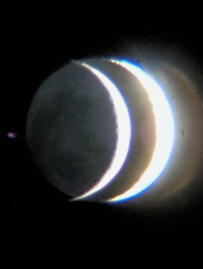 a photo of a crescent moon, purposefully overexposed to show the dim part of the moon