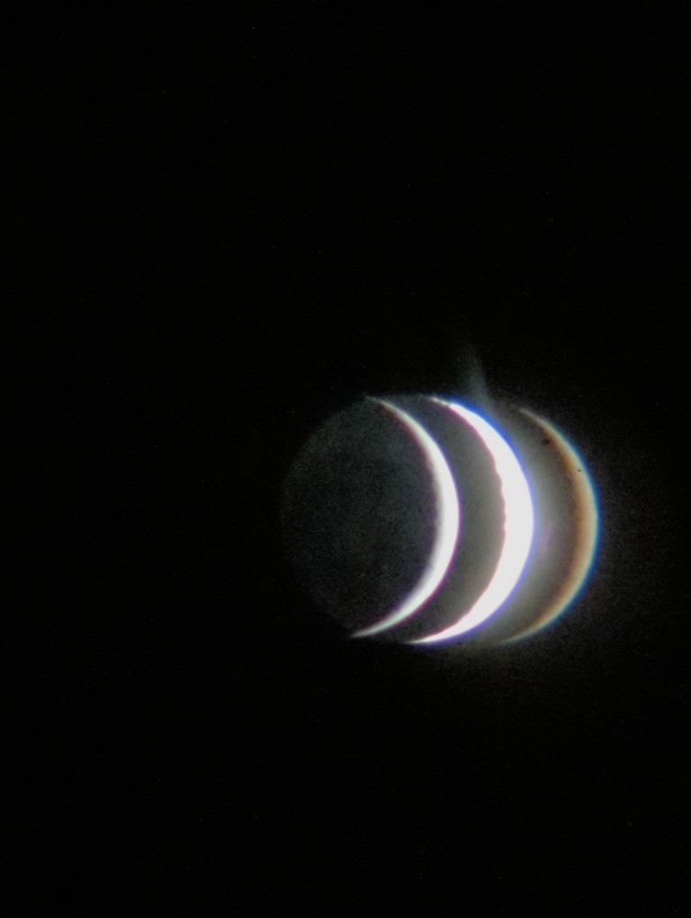 the moon crescent with 3 visible reflections side by side